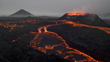 Lavaspeiender Vulkan, im Vordergrund glühende Lavaflüsse