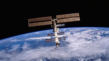Die Internationale Raumstation im All, im Hintergrund die Erde