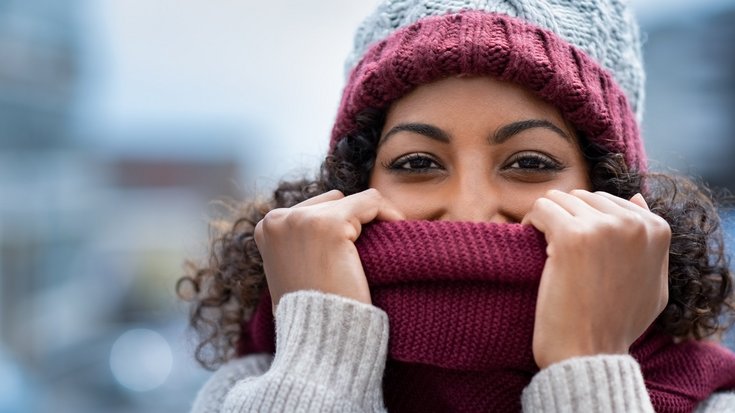 Auf dem Foto ist eine Frau im Wollpulli zu sehen, die eine Wollmütze und einen Wollschal trägt.