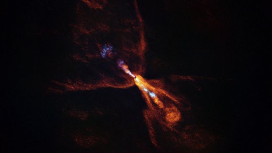 Sowohl Kohlenmonoxid (orange) als auch Siliziummonoxid (blau) strömen vom Stern HOPS-315 weg | Bildquelle: ALMA(ESO/NAOJ/NRAO)/M. McClure et al. Heller Punkt im All, von dem schmetterlingsförmige und kleinere Schwaden wegströmen
